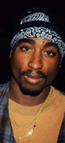 a close up of a man wearing a bandana and a chain .