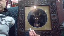 a person holding a picture frame with a picture of a horned animal on it