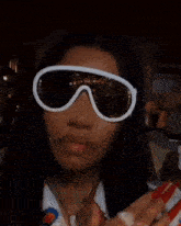 a close up of a woman wearing sunglasses and a ring on her finger .