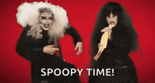 two drag queens are standing next to each other on a red background holding a doll .