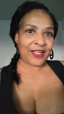 a woman wearing a black shirt and earrings smiles for the camera