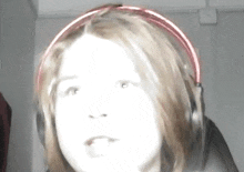 a girl wearing headphones looks at the camera with a surprised look on her face