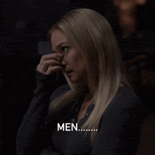 a woman wipes her nose with her hand and the word men is visible in the corner