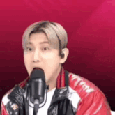 a man in a red jacket is singing into a microphone and making a funny face .