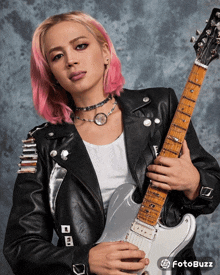 a woman with pink hair is holding a guitar with a fotobuzz logo in the background