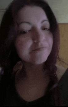 a woman with long red hair is making a funny face while looking at a cell phone .