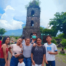 a group of people are posing for a picture in front of a stone tower with the number 96 on their shirt