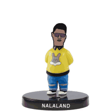 a figurine of a man wearing a yellow sweater with a bunny on it and the name nalaland