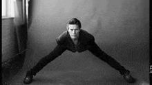 a black and white photo of a man in a suit doing push ups .