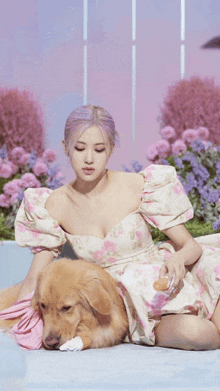 a woman in a floral dress is laying on the floor with a dog