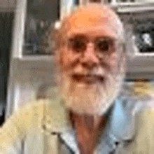 an older man with a beard and glasses is smiling for the camera .