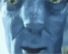 a close up of a man 's face with blue paint on it and yellow eyes .