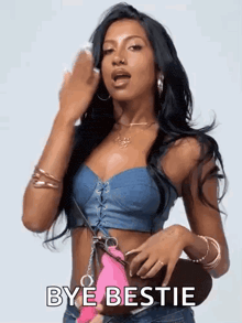 a woman in a denim crop top is holding a pink purse and says bye bestie