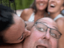 a man with glasses is kissed by two women