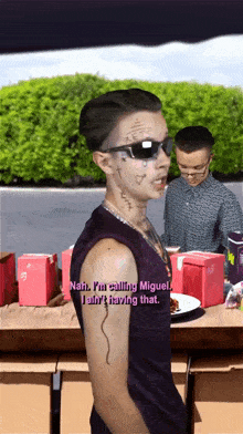 a man with a tattoo on his arm is standing in front of a table with boxes and a plate of food