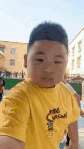 a young boy wearing a yellow shirt with the simpsons on it is taking a selfie