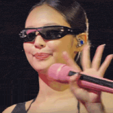 a close up of a woman wearing sunglasses and holding a pink microphone