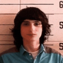 a young man with long hair is posing for a picture in front of a police line .