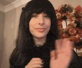 a woman with long black hair and a nose ring waving her hand