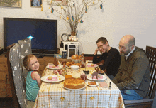 a little girl sits at a table with three men