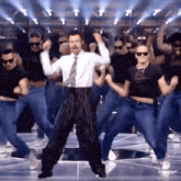 a man in a suit and tie is dancing in front of a group of people