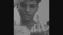 a young man is giving the middle finger to the camera .