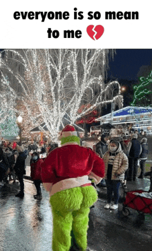 a grinch costume is standing in front of a crowd of people .