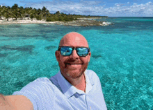 a man wearing sunglasses is taking a selfie in the water