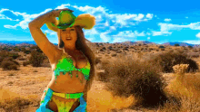 a woman in a bikini and cowboy hat is in the desert
