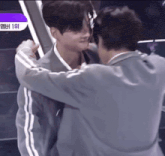 two men are hugging each other with a purple sign in the background that says ' 1st '