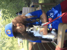 a girl wearing a blue shirt that says ' sd ' on it holds a small dog