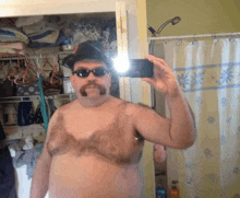 a man with a mustache and sunglasses takes a selfie in front of a shower curtain