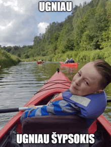 a boy sits in a kayak with the words ugniau written on the bottom