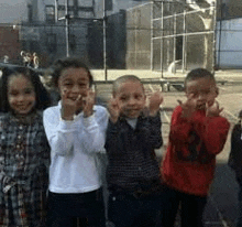 a group of children are standing next to each other in a playground and giving the middle finger .