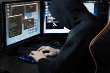 a person in a hoodie is typing on a keyboard