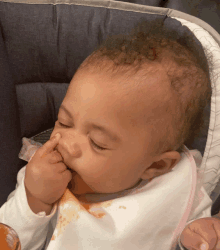 a baby in a high chair with a bib on eating