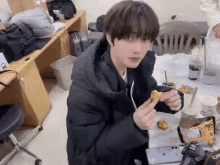 a young boy is sitting at a table eating a sandwich .