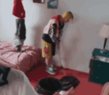 a man is playing golf in a bedroom while a child stands on a bed .