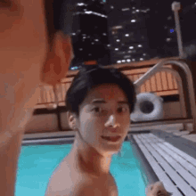 a shirtless man is standing next to a swimming pool .