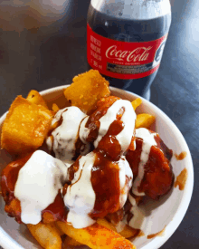 a bottle of coca cola sits next to a plate of food