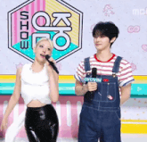 a woman singing into a microphone next to a man holding a microphone that says " gyujin " on it