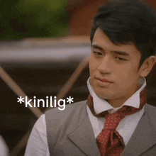 a man wearing a vest and tie has the word * kinilig * on the bottom right