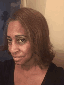 a woman with brown hair is taking a selfie in front of a mirror in a bathroom .