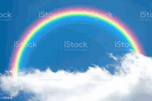 a rainbow in a blue sky with white clouds royalty free