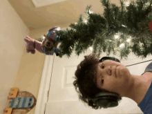 a boy wearing headphones is standing next to a christmas tree