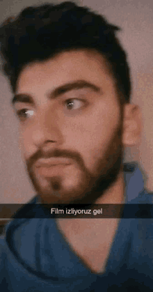 a man with a beard is wearing a blue shirt and has a caption that says film izliyoruz gel .