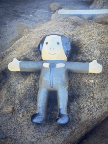 a stuffed monkey laying on a rock with his arms outstretched