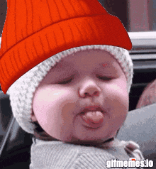 a baby wearing a red hat is sticking out its tongue