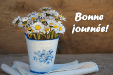 a bouquet of daisies in a blue and white vase with the words bonne journee written above it