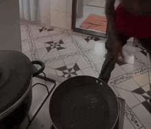 a black pot sits on a stove next to a frying pan on a tiled floor